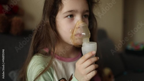 The girl inhales the medicine through the inhaler. Bronchitis treatment. Breathing relief.