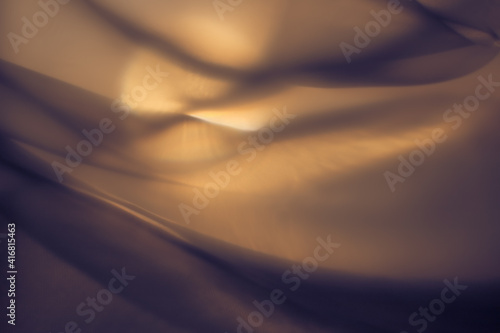 Abstract yellow, orange art background, silk texture and wave lines in motion for a classic luxury design. Imitation of the setting sun outside the window.