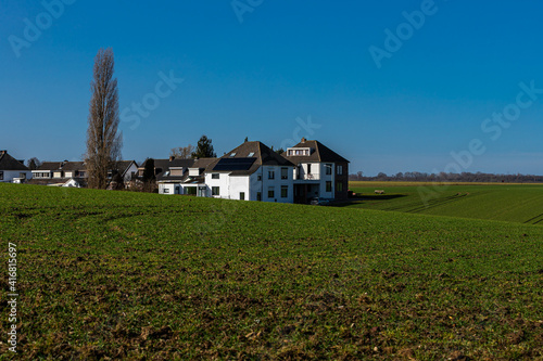 A small village with white houses in a valley near Maastricht in the middle of the agricultural fields. The village looks like an oases in the middle of nowhere