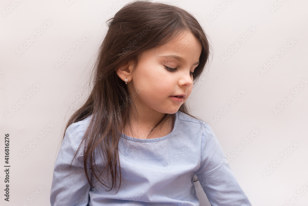 Little girl sitting looking to the side on a white background