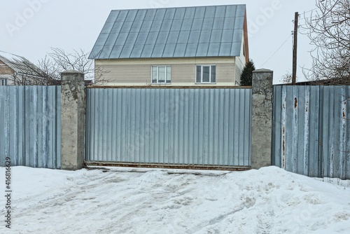 gray metal gate and part of a wall fence in white snow on a winter street