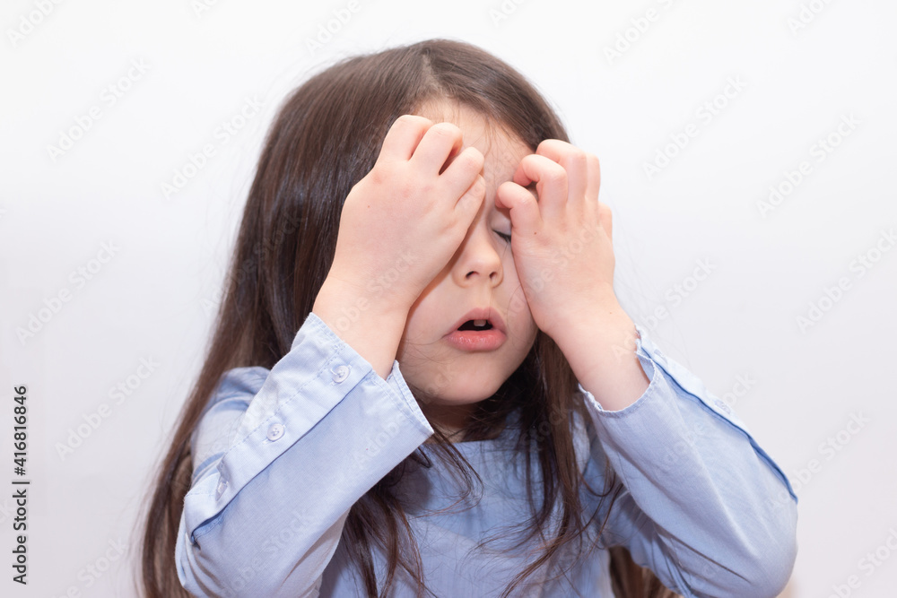 Beautiful little cute girl with long smooth hair in a frightened way closed her eyes with her hands Beautiful little cute girl with long smooth hair in a frightened way closed her eyes with her hands