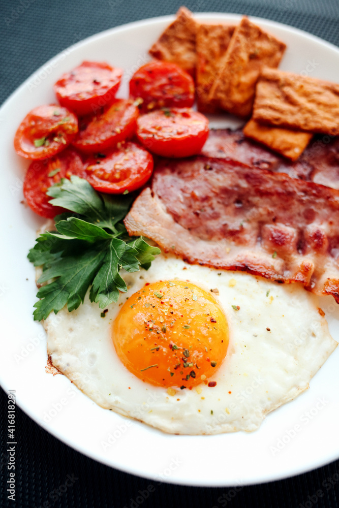English breakfast - fried eggs, herbs, tomatoes, bacon and crackers English breakfast - fried eggs, herbs, tomatoes, bacon and crackers