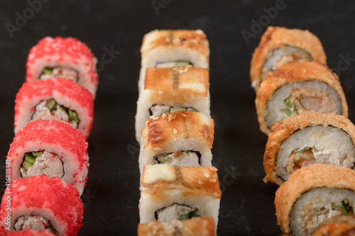 Three different sushi rolls placed on black surface