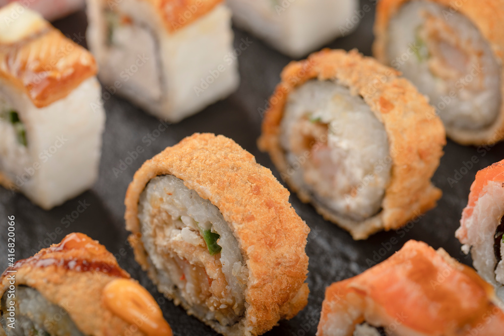 Set of mix sushi rolls placed on black surface Set of mix sushi rolls placed on black surface