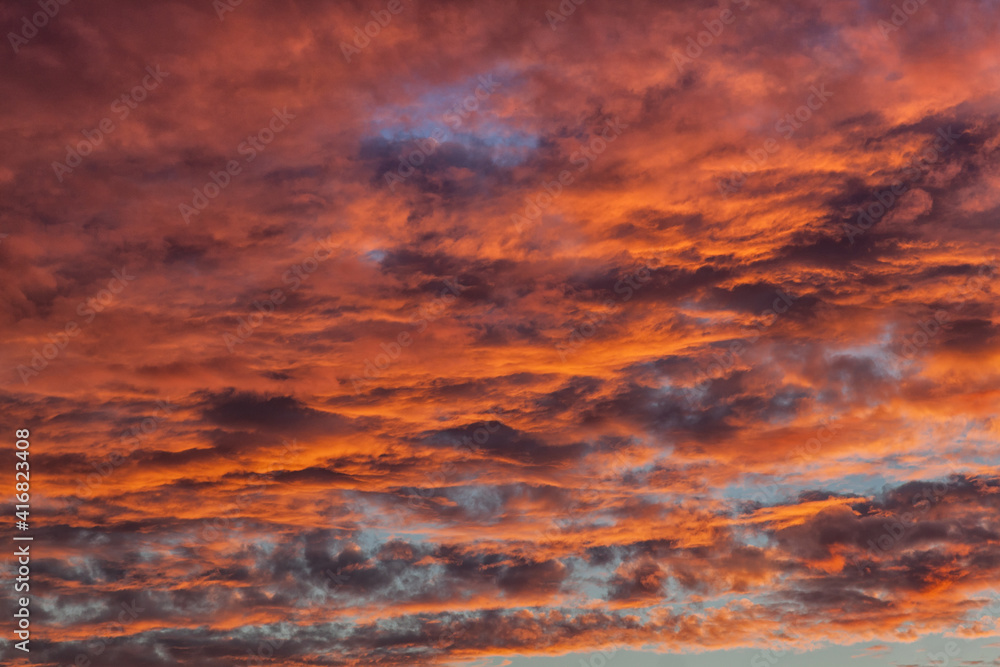 Background photo of dark blue sky in the evening with  orange and red shade of the sunset. Beautiful and natural clouds formation.