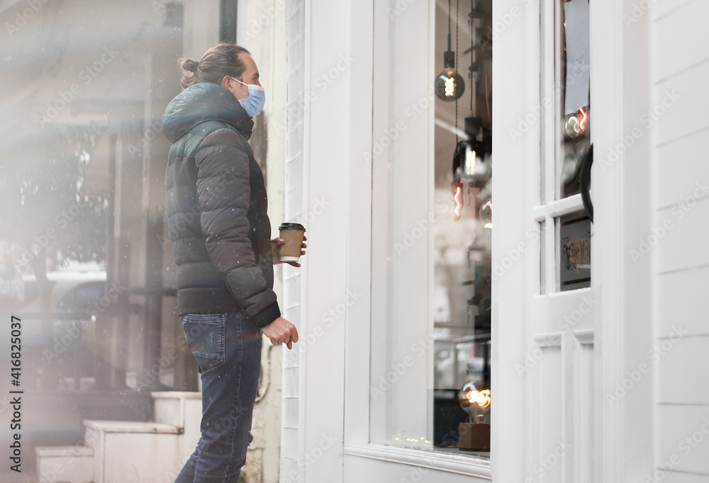 A man with a face mask stands near close store