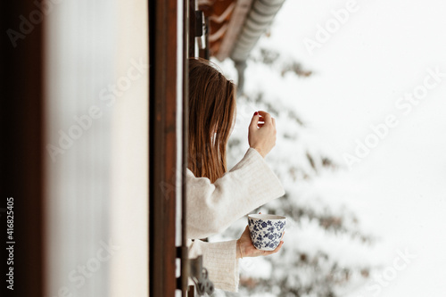 Femme prenant le café à la fenêtre sous la neige photo