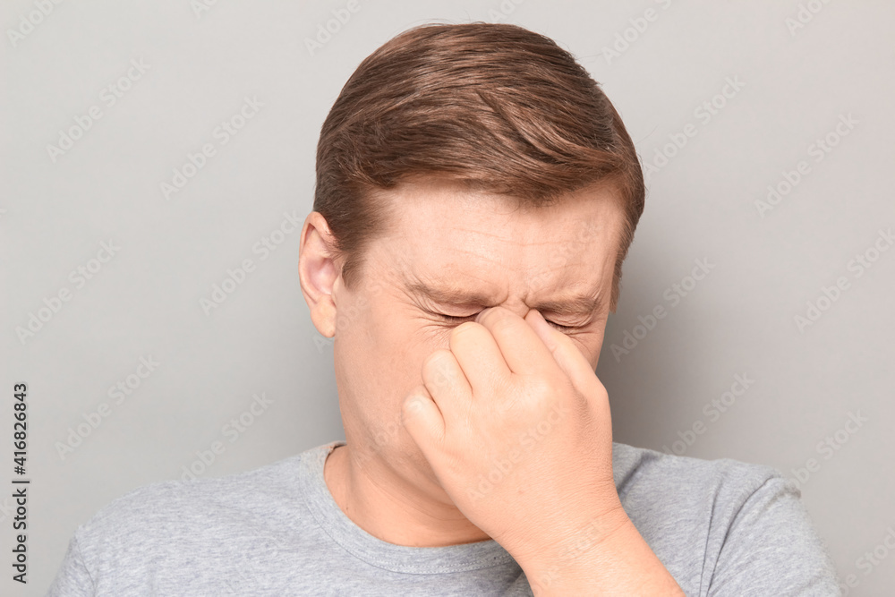 Portrait of unhappy tired man touching bridge of nose, squinting eyes Portrait of unhappy tired man touching bridge of nose, squinting eyes