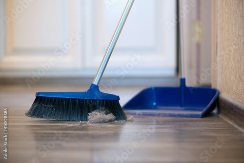Broom brush and dustpan on the floor. Home cleaning.