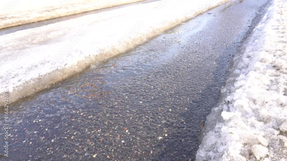 A car track in the snow melts under the spring sun and exposes the asphalt A car track in the snow melts under the spring sun and exposes the asphalt