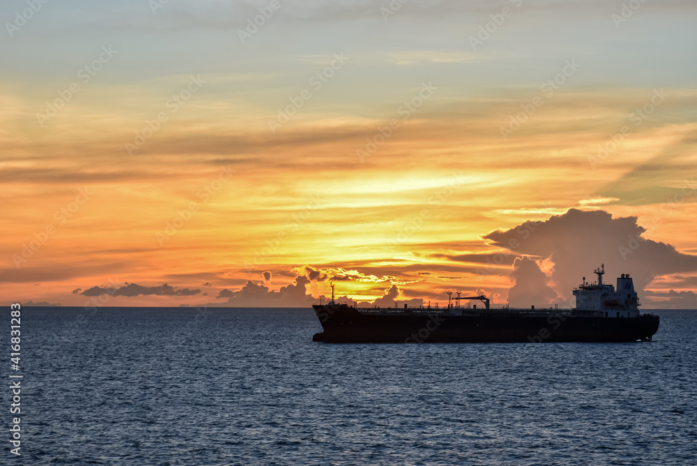 Silhouette of the cargo ship on a beautiful sunset background.