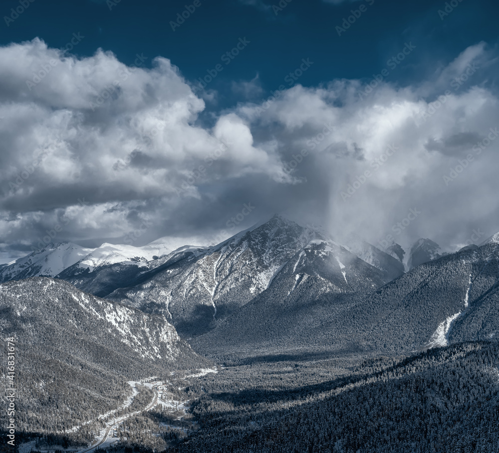 Caucasus Mountains. View from the Northern slope of the Arkhyz ski resort to the snowy mountain forests. Panoramic view of Arkhyz. Winter mountain landscape. A snow cloud over the mountain.