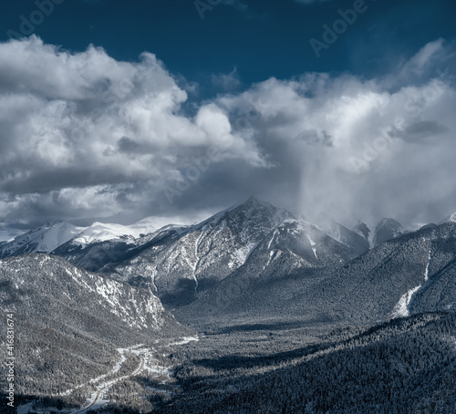 Caucasus Mountains. View from the Northern slope of the Arkhyz ski resort to the snowy mountain forests. Panoramic view of Arkhyz. Winter mountain landscape. A snow cloud over the mountain.