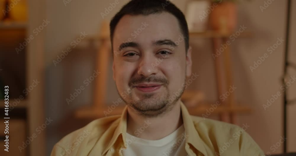 Crop view of happy man turning head and looking to camera. Positive male adult person posing and laughing while sitting at home in evening.Concept of people portrait and emotions. Crop view of happy man turning head and looking to camera. Positive male adult person posing and laughing while sitting at home in evening.Concept of people portrait and emotions.