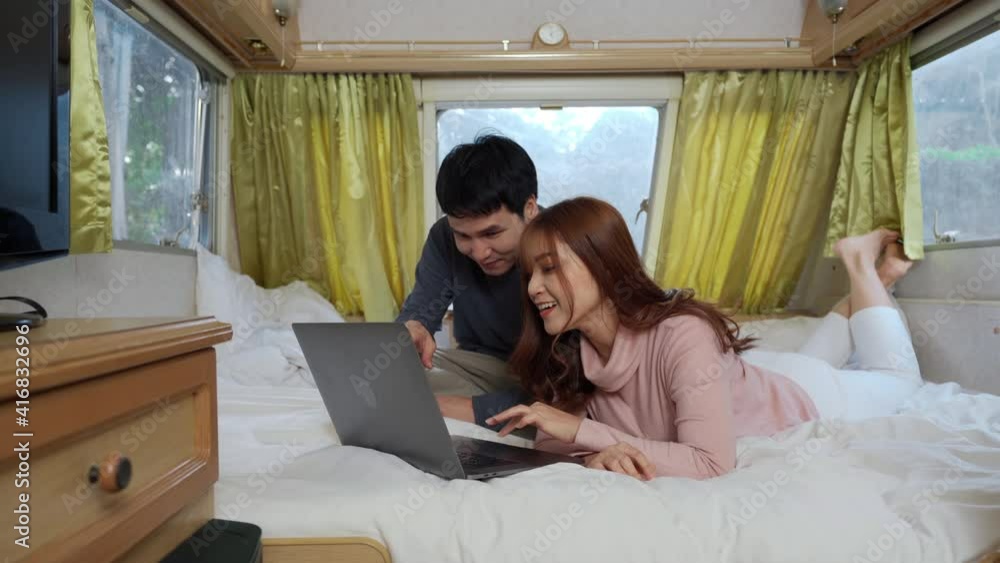 young couple using laptop computer on bed of a camper RV van motorhome young couple using laptop computer on bed of a camper RV van motorhome