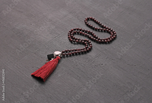Rosary mala 108 beads from natural stones Garnet lie on black modern background. Author's jewelry from natural stones, Buddhism, matra, prayer, rosary from stones for prayer, beauty. Long beads photo