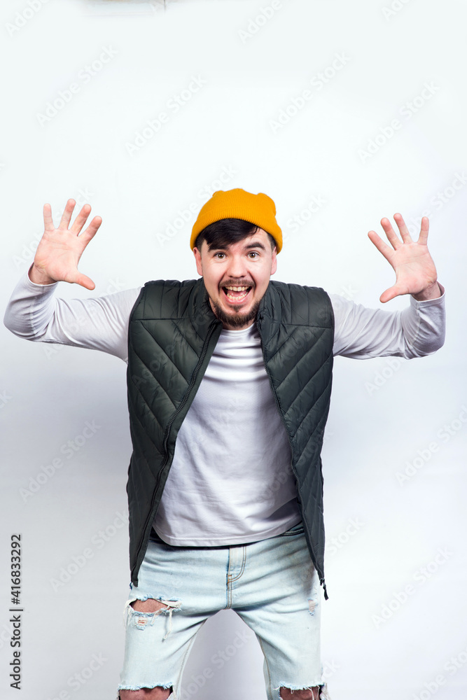 young handsome man in a stylish vest and white t-shirt raised his hands up smiling
