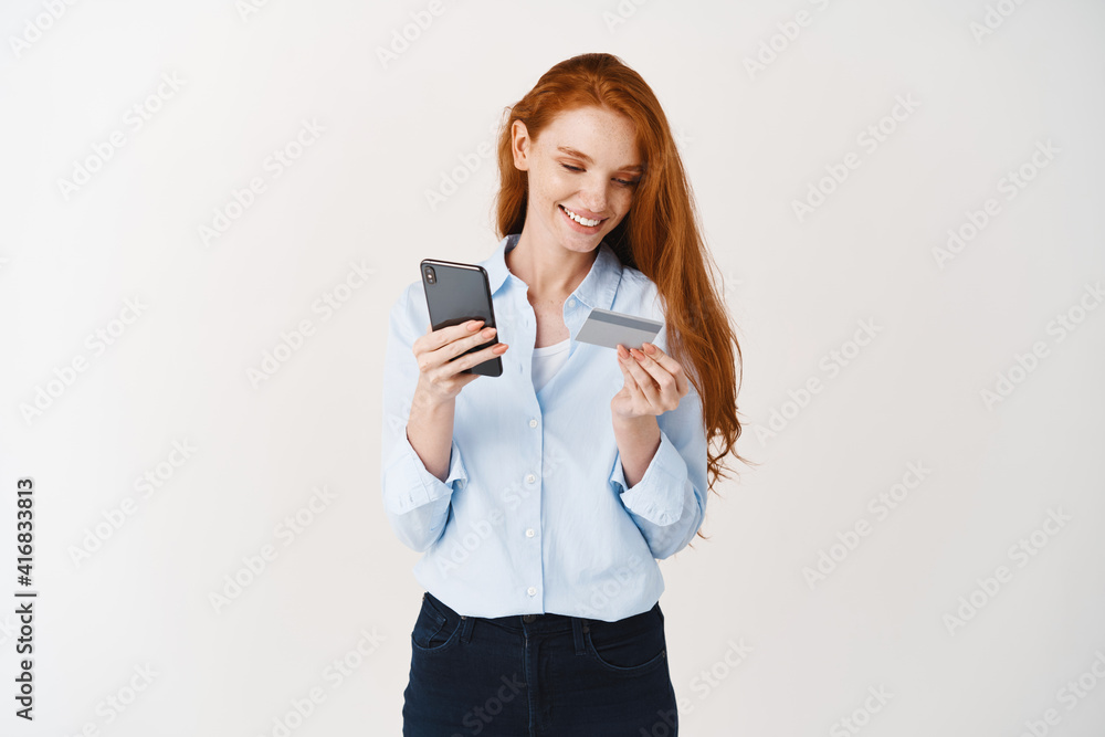 Young attractive woman shopping online with smartphone and plastic credit card, making purchase in internet, white background Young attractive woman shopping online with smartphone and plastic credit card, making purchase in internet, white background