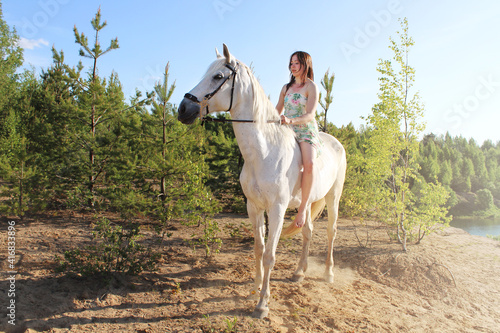 Young girl sits on a white horse without a saddle