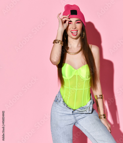 Studio portrait of beauty model fashion girl stylish teenager isolated on a pink background. Happy charming young woman with joyful facial expression showing tongue. Adolescence and adolescence © FAB.1