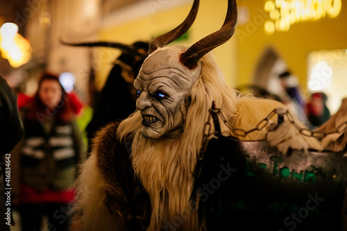 Krampus night parade, People in scary fur costumes and masks with hornes walk on the street, Traditional show before Christmas, historical street Getreidegasse, Salzburg, Austria