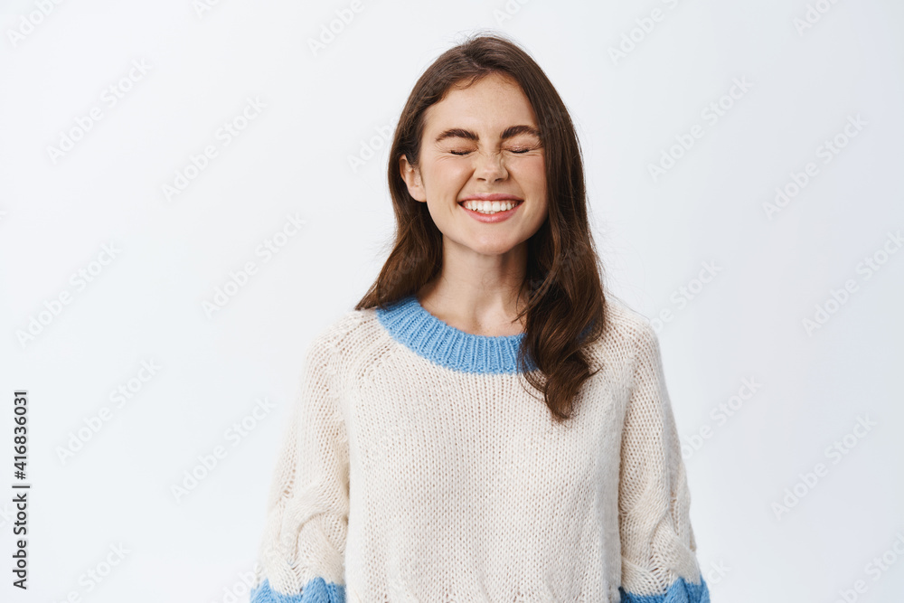 Portrait of happy girl showing perfect white smile teeth, close eyes and standing carefree, enjoying and having fun, standing in sweater against studio background Portrait of happy girl showing perfect white smile teeth, close eyes and standing carefree, enjoying and having fun, standing in sweater against studio background