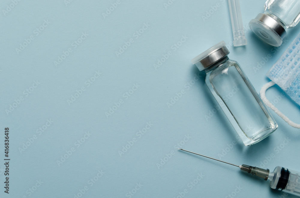 Medical concept, jars with covid vaccine, syringe, on a blue background. Place for text.Immunization and treatment of coronavirus infection. Medical concept, jars with covid vaccine, syringe, on a blue background. Place for text.Immunization and treatment of coronavirus infection.