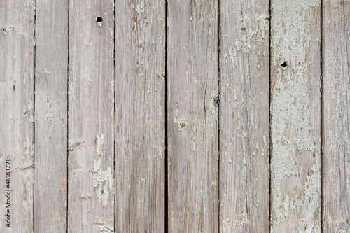 Part of an old fence of painted wooden boards on the street. Old wooden fence made of flat boards. Faded texture with peeling paint. Copy space