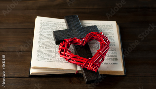 Open book holy bible on a wooden table. Scripture. Wooden cross of Jesus and red heart.