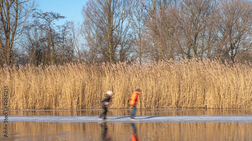 people ice skating on frozen river during sunny winter day