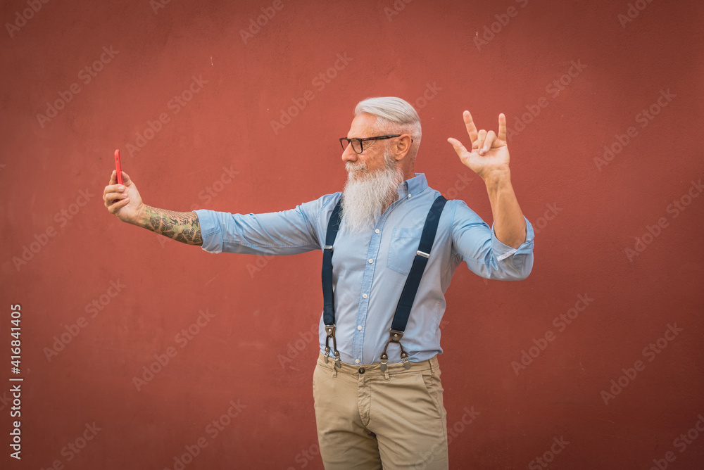 an older man in hipster clothes and glasses and a long white beard walks around talking on the phone focus on head an older man in hipster clothes and glasses and a long white beard walks around talking on the phone focus on head