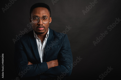 portrait of attractive, beautiful, serious and stylish professional African American businesswoman in dark suit and white shirt isolated on dark background. Low key. Selective focus