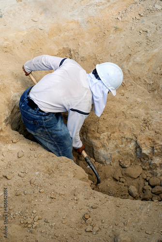 Worker digging a trench with a shovel