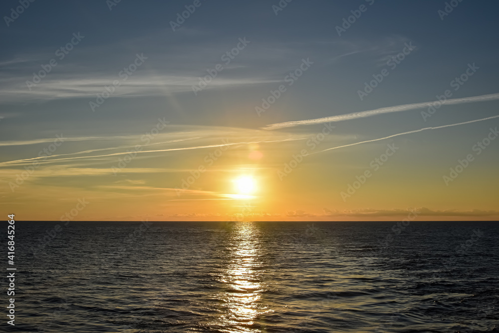 Sunset over the calm sea in a cloudy sky. Abstract and dramatic sunset sky.