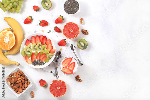 Fototapeta Naklejka Na Ścianę i Meble -  Healthy breakfast with ingredients, fruit salad with strawberries, muesli, grapes, banana and chia seeds for weight loss. The concept of natural nutrition and detox diet, lifestyle, selective focus,