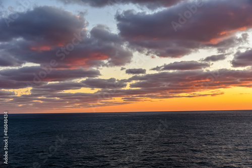 Sunset over the calm sea in a cloudy sky. Abstract and dramatic sunset sky.