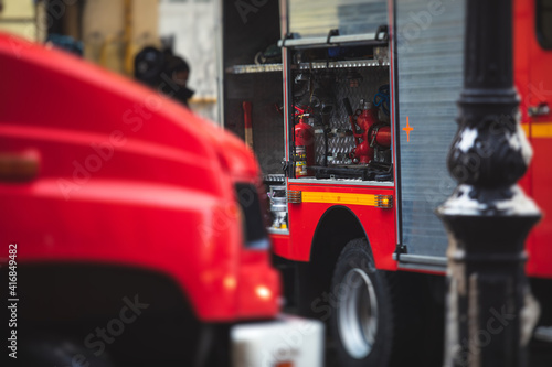 Group of fire men in uniform during fire fighting operation in the city streets, firefighters with the fire engine truck fighting vehicle in the background, emergency and rescue