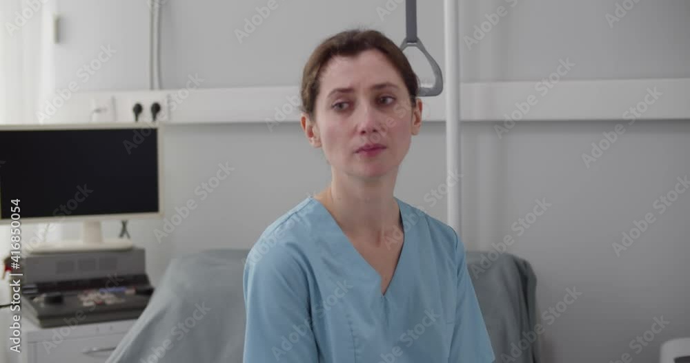 Upset crying female nurse sitting on empty hospital bed Upset crying female nurse sitting on empty hospital bed