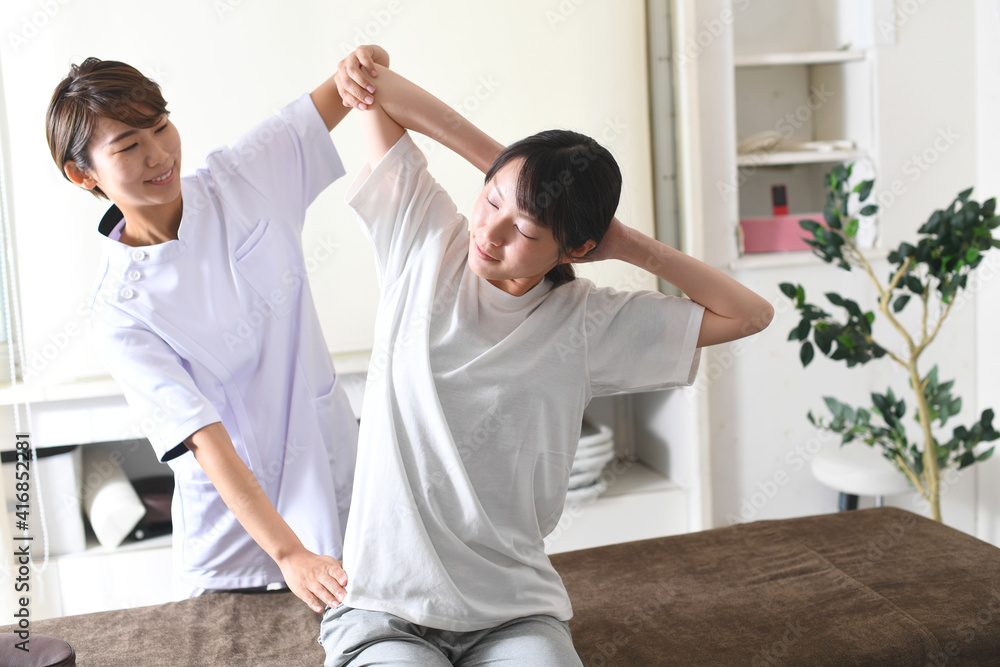 Obraz premium 整体（カイロプラクティック）を受けるストレッチ中の若い女性