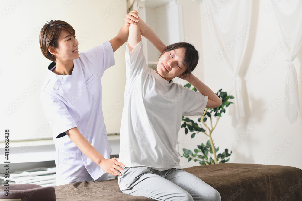 Obraz premium 整体（カイロプラクティック）を受けるストレッチ中の若い女性