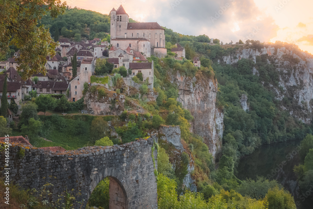Sunset or sunrise view of the scenic hilltop medieval French village of Saint-Cirq-Lapopie, France with the fortified church above the Lot River.