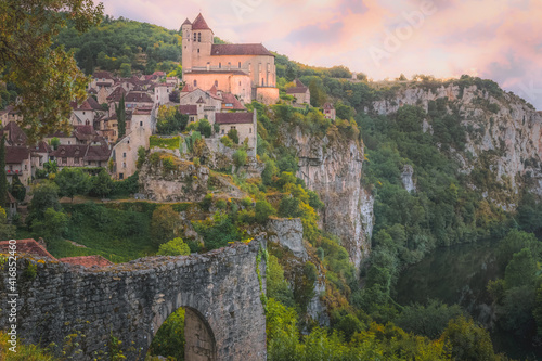 Sunset or sunrise view of the scenic hilltop medieval French village of Saint-Cirq-Lapopie, France with the fortified church illuminated above the Lot River.