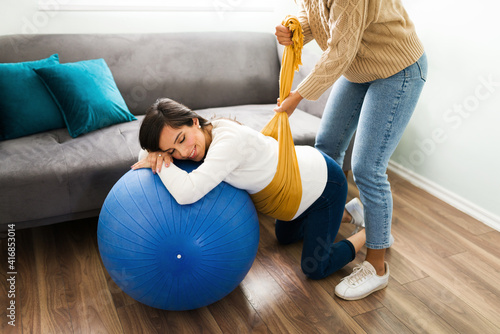 Pregnant woman relaxing while a midwife wraps a rebozo in her belly