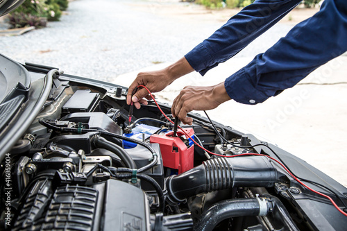 Close up hand of auto mechanic are using measuring equipment tool for checking car battery. Concepts of car fix repair and service maintenance.