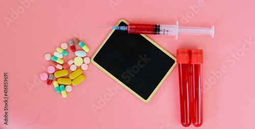 First aid kit on color background with blank blackboard