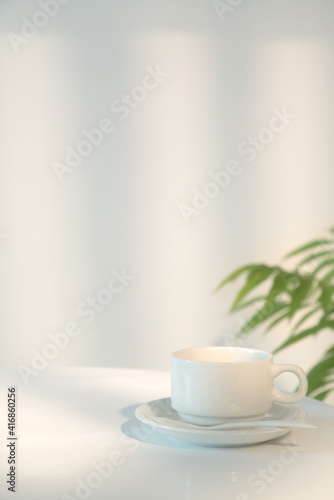 A cup of coffee on the table on beige background, morning sunlight through the window shining on the wall, copy space