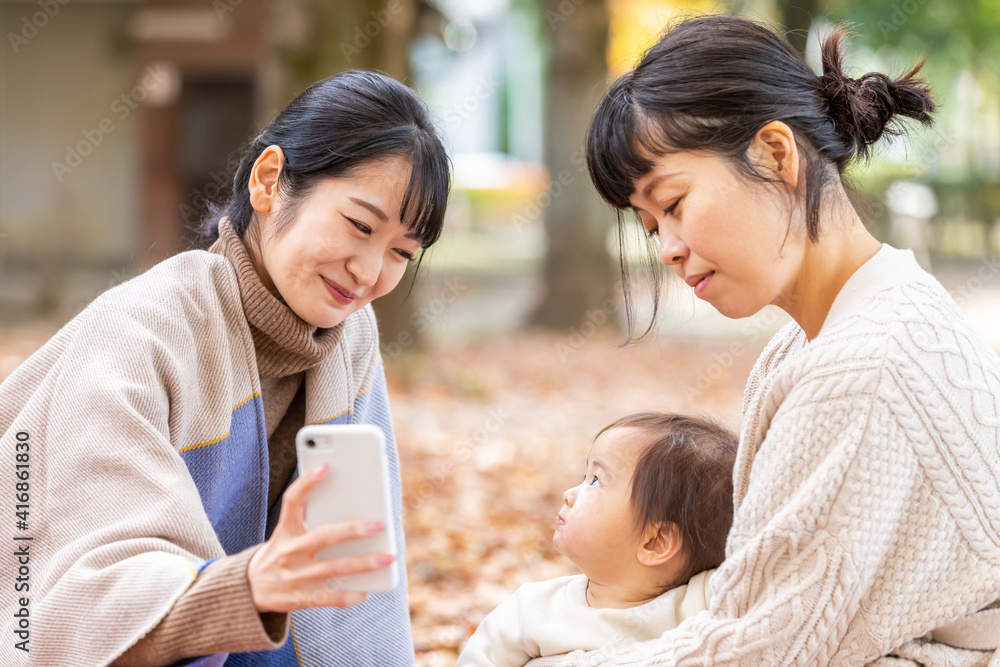 公園でスマホを見ながらママ友と話す女性
公園でスマホを見ながらママ友と話す女性