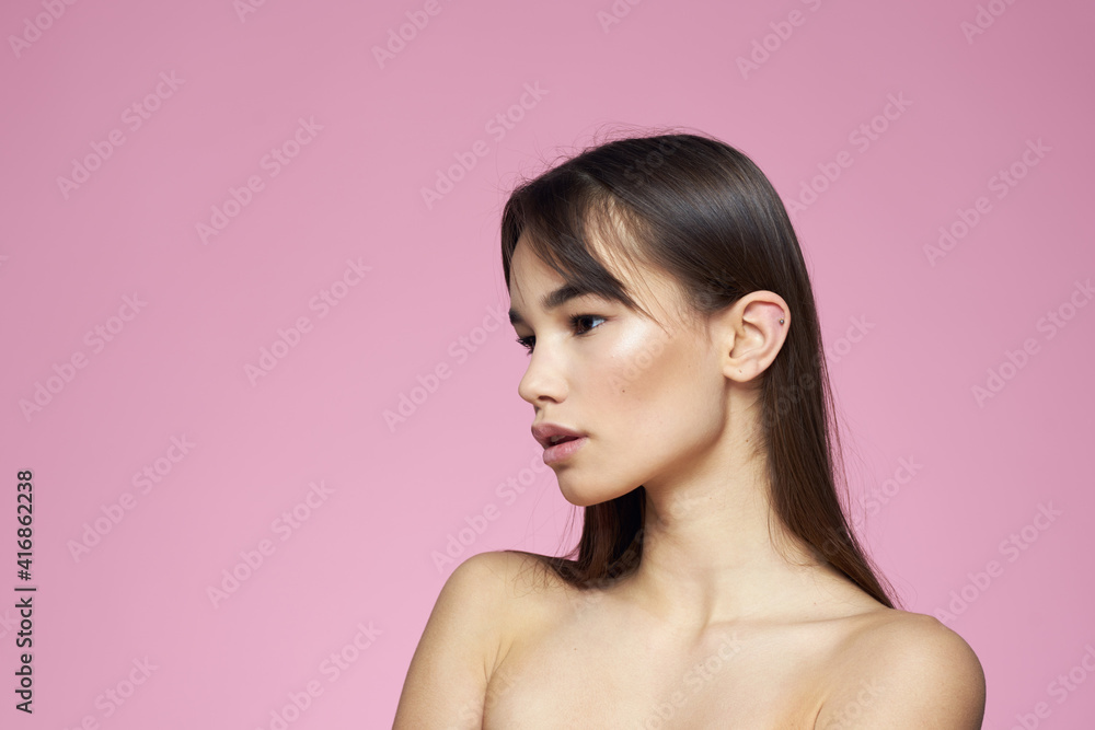 Woman with bare shoulders hair care makeup clean skin pink background Woman with bare shoulders hair care makeup clean skin pink background