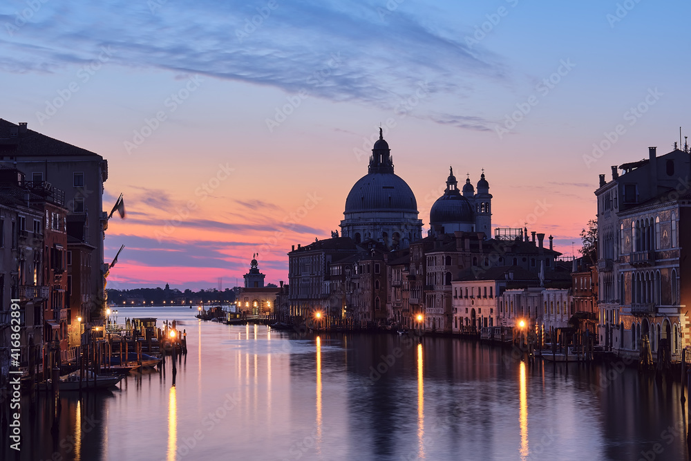 Fototapeta Romantyczna Wenecja nocą. Obraz miejski Canal Grande w Wenecji, z bazyliką Santa Maria della Salute odzwierciedlenie w spokojnym morzu. Światła łodzi pasażerskiej na wodzie.